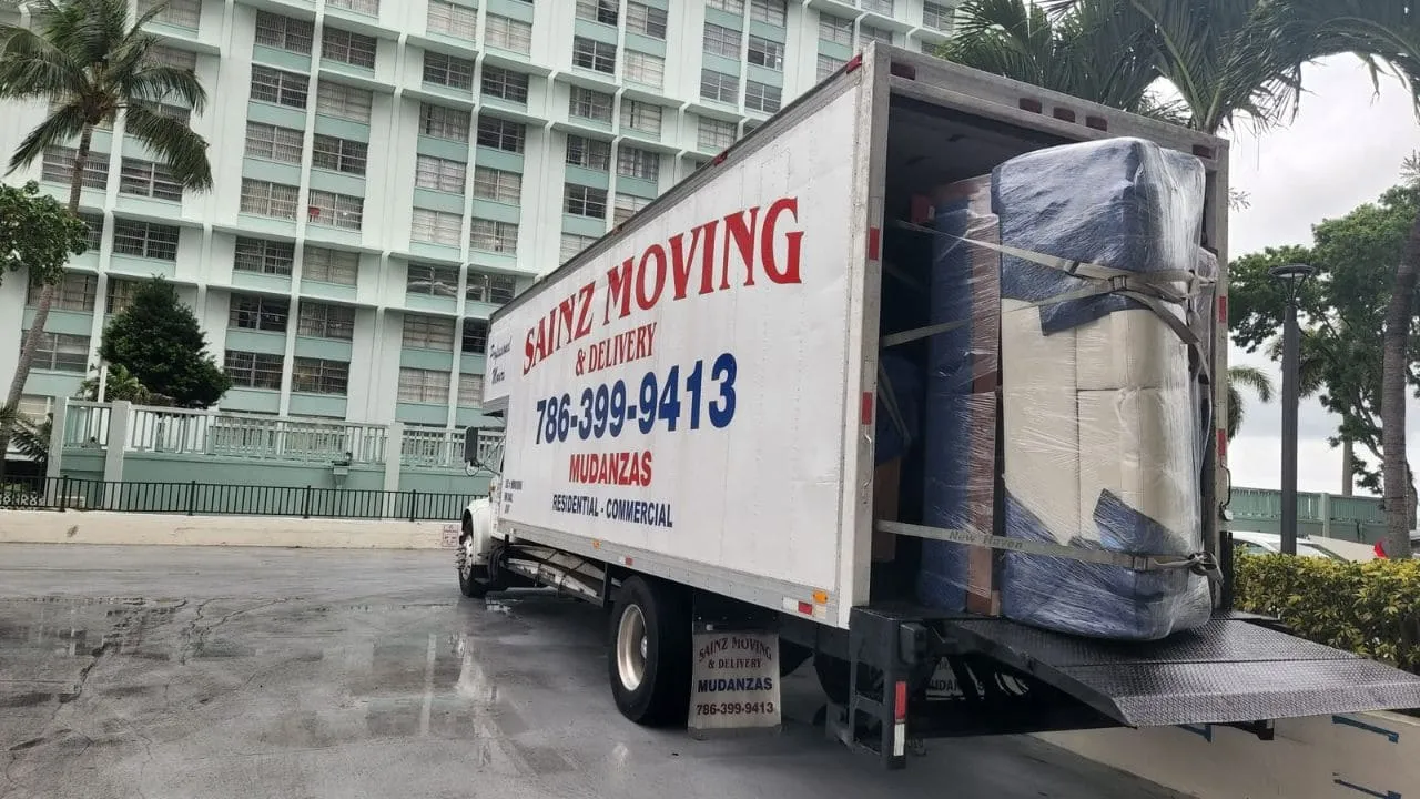 Sainz Moving truck being loaded with wrapped furniture at a high-rise